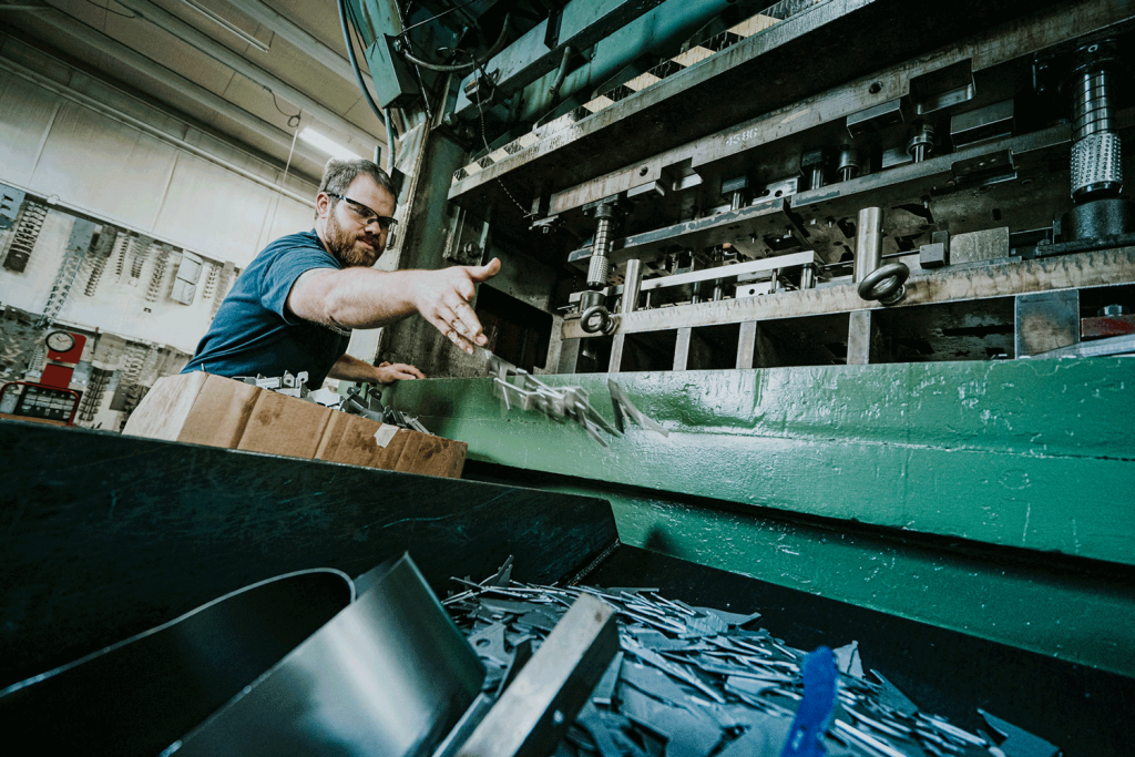 A man operating machinery in a metal factory, diligently working on production tasks.