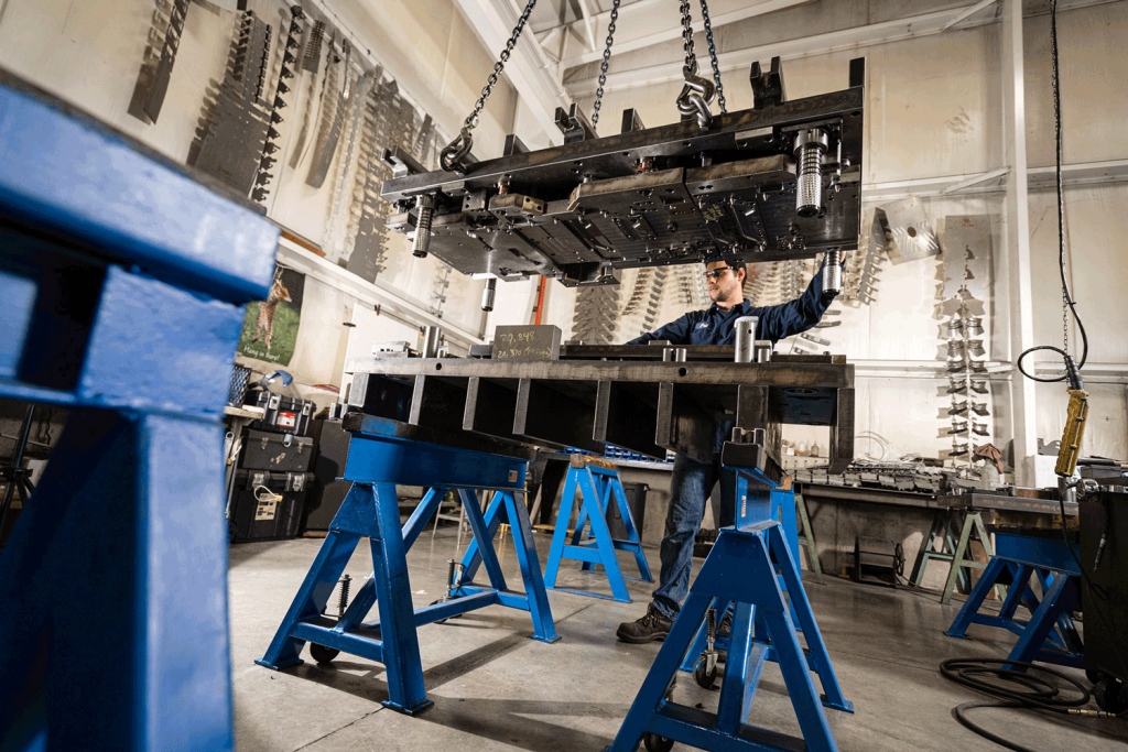 A young man wearing goggles operating a stamping press.