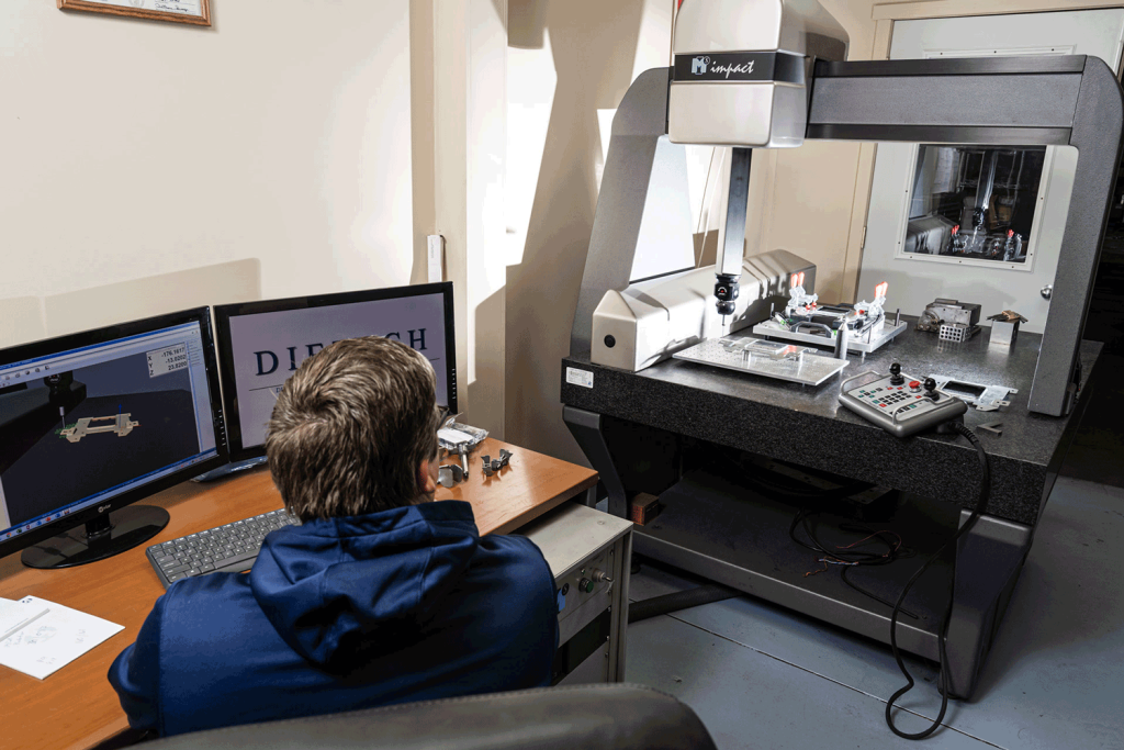 A man sitting in front of a computer displaying a CAD drawing.