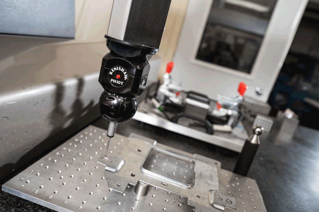 A drill hovering above a metal plate with holes in it.