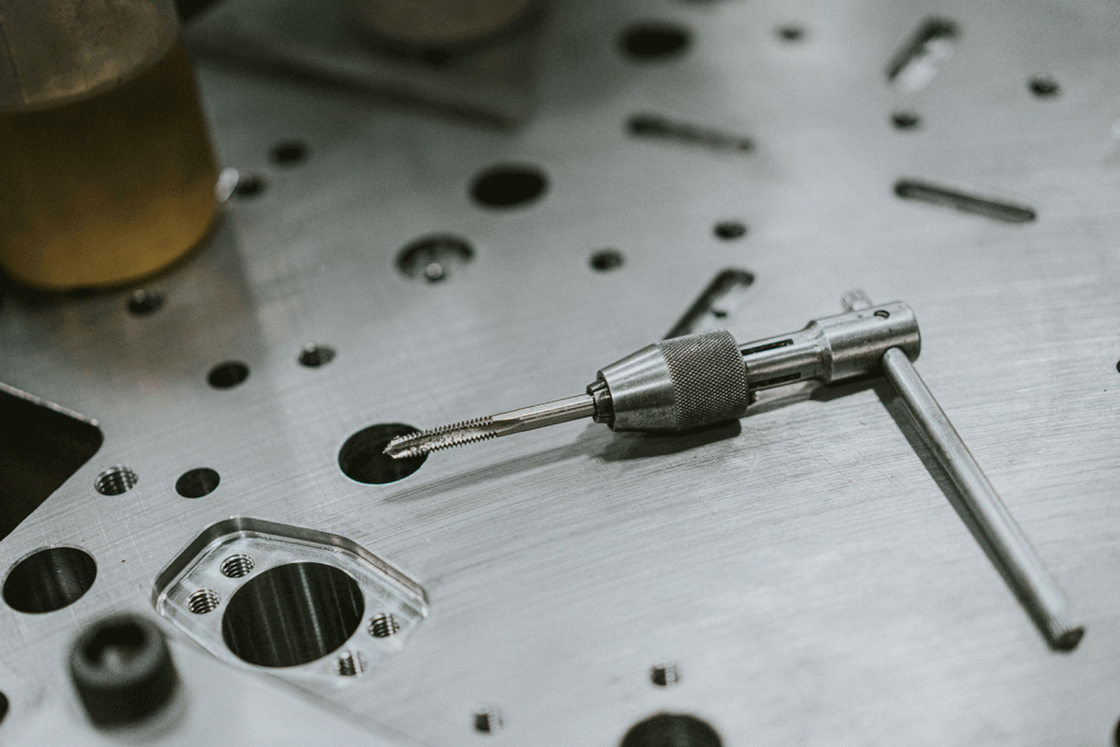 A hand drill laying on top of a stamping die.