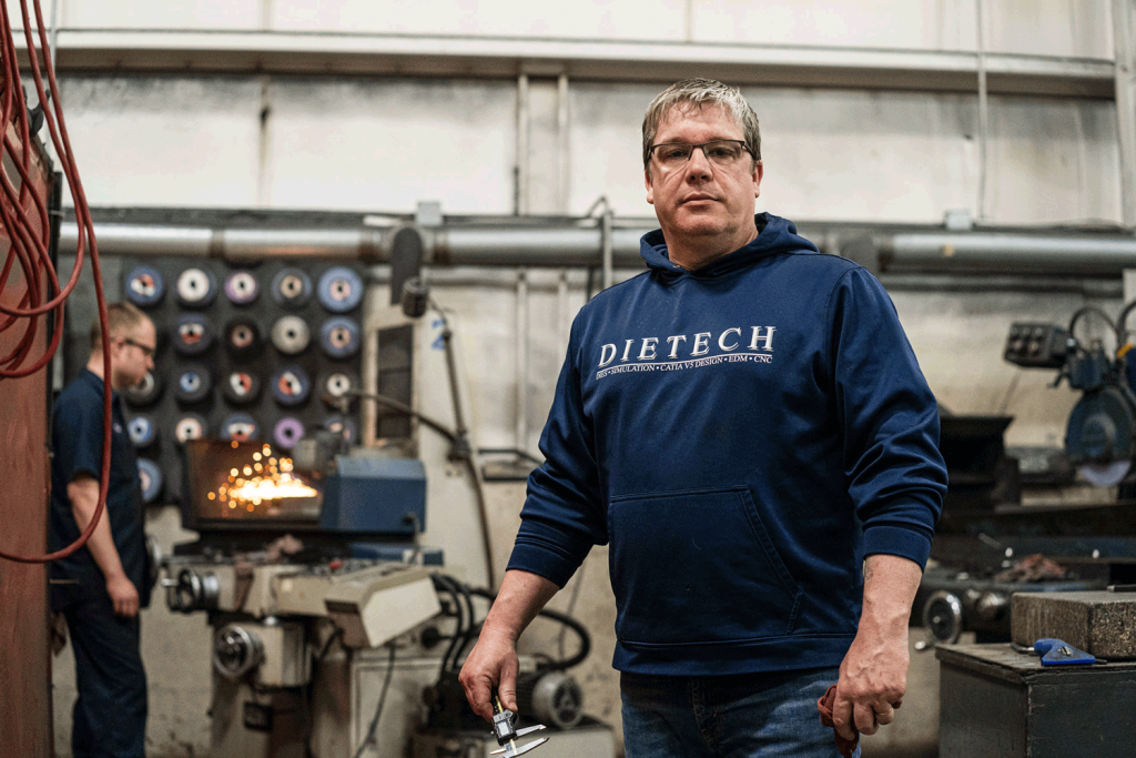 Blue sweatshirt-clad man in industrial setting.
