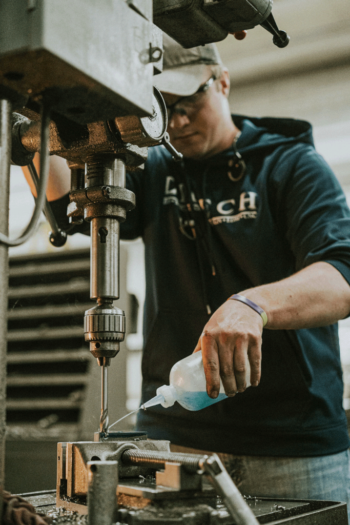 A man in a blue shirt diligently operates a drill-press