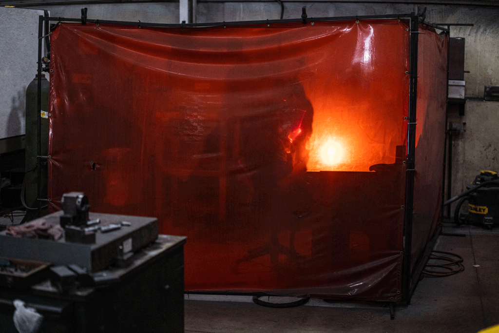 The yellow flame of a welding torch behind a transluscent amber screen.