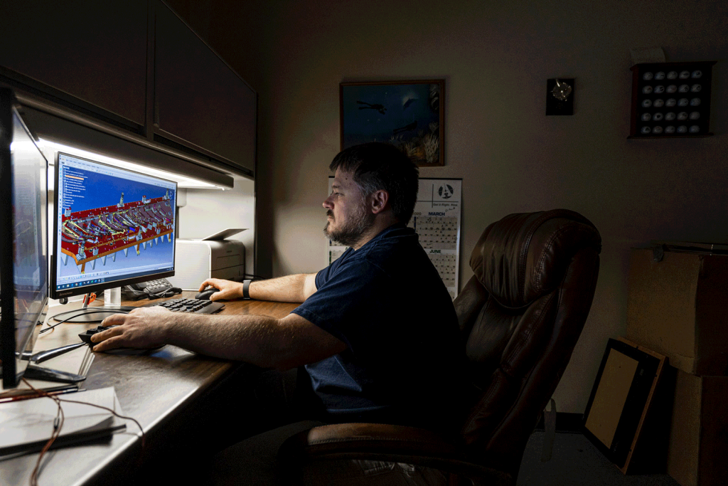 A man working with CAD software on a computer at his desk.